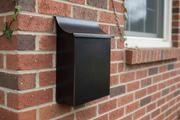Dark patina vertical copper mailbox on brick wall