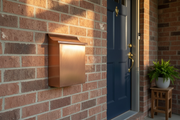 Handmade vertical brushed copper mailbox installed on residential house wall